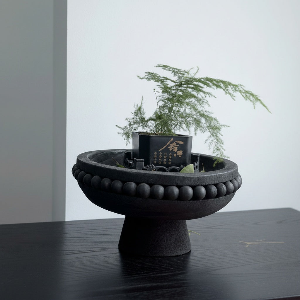 Black wooden beaded pedestal bowl styled with greenery on modern tabletop