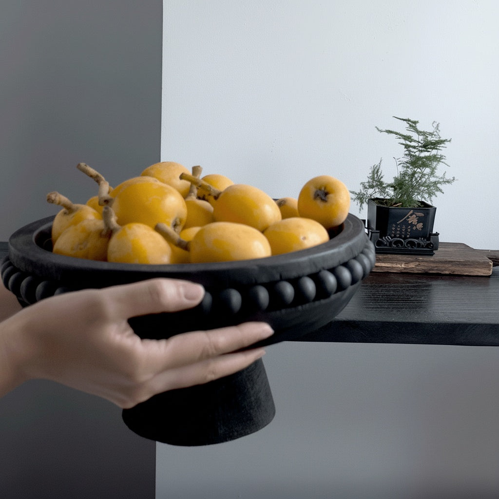 Matte black wooden pedestal centerpiece bowl held with oranges inside