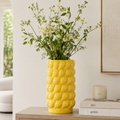Large yellow ceramic lemon textured decorative vase styled with white flowers and greenery for modern home decor