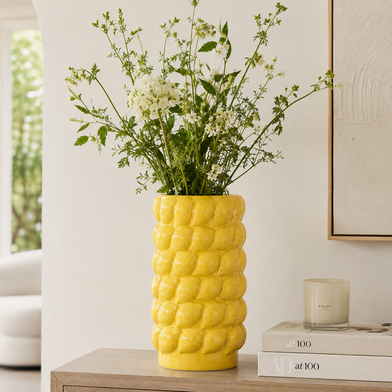 Large yellow ceramic lemon textured decorative vase styled with white flowers and greenery for modern home decor