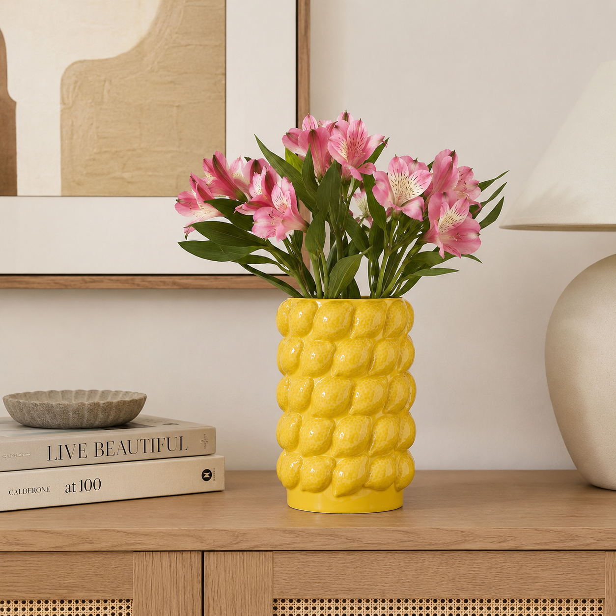 Medium yellow ceramic lemon textured vase with pink flowers on a modern console table