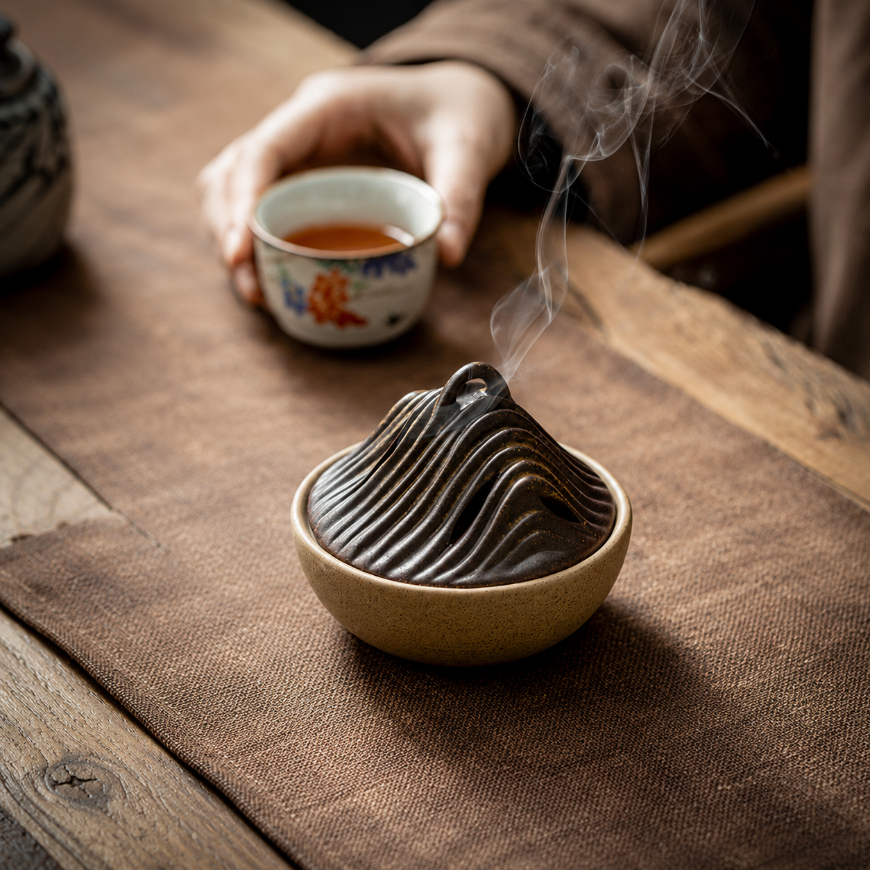 Zen ceramic incense burner with tea cup and smoke on wooden table