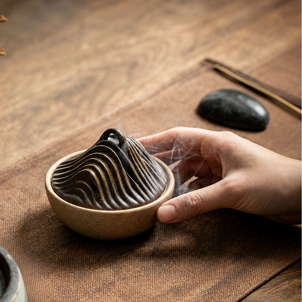 Hand placing Smoked Brown ceramic incense burner on tea table