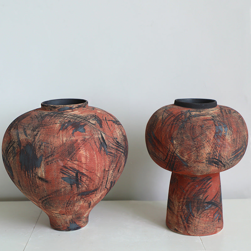 Front view of two distressed red and black ceramic vases