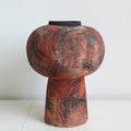 Close up of pedestal distressed ceramic vase with abstract markings