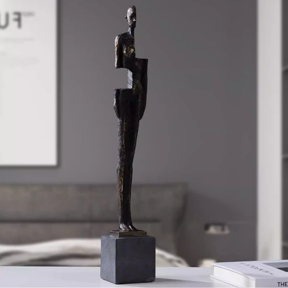 Antique bronze resin abstract human figure sculpture displayed on a bedside table