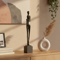 Antique bronze resin abstract figure sculpture styled on a console table with vase decor