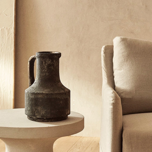Aged black stone pitcher vase styled on side table