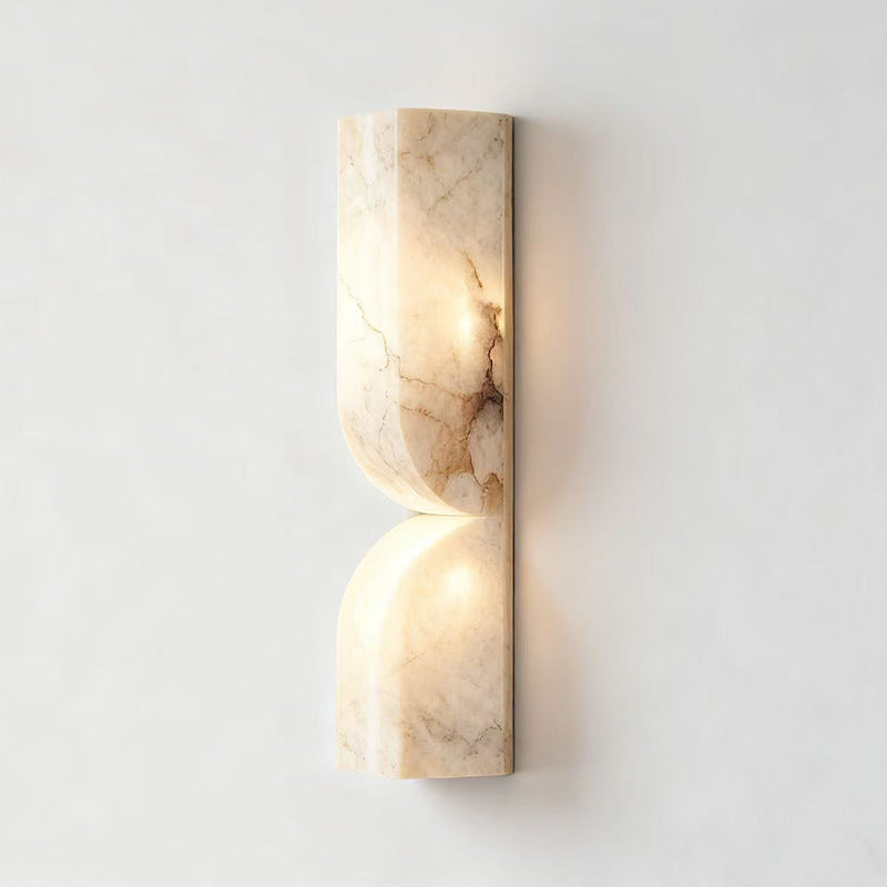 Front view of alabaster curved wall sconce with warm illumination