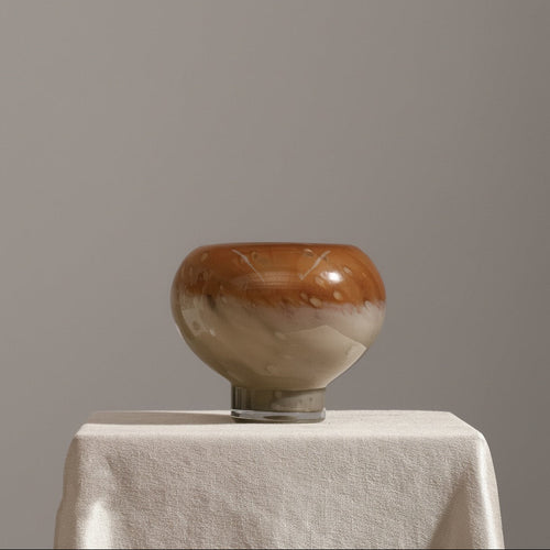 Empty amber and cream art glass bowl vase on display