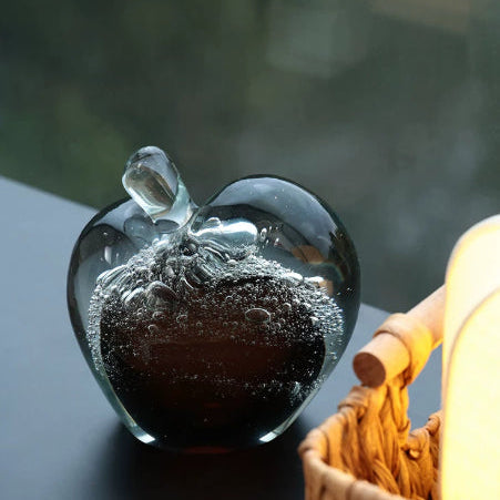 High angle view of glass apple paperweight on dark surface