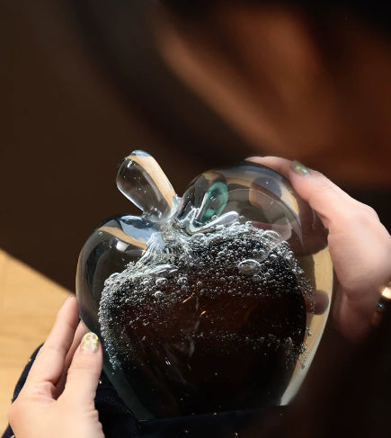 Hands holding heavy glass apple sculpture showing scale and transparency