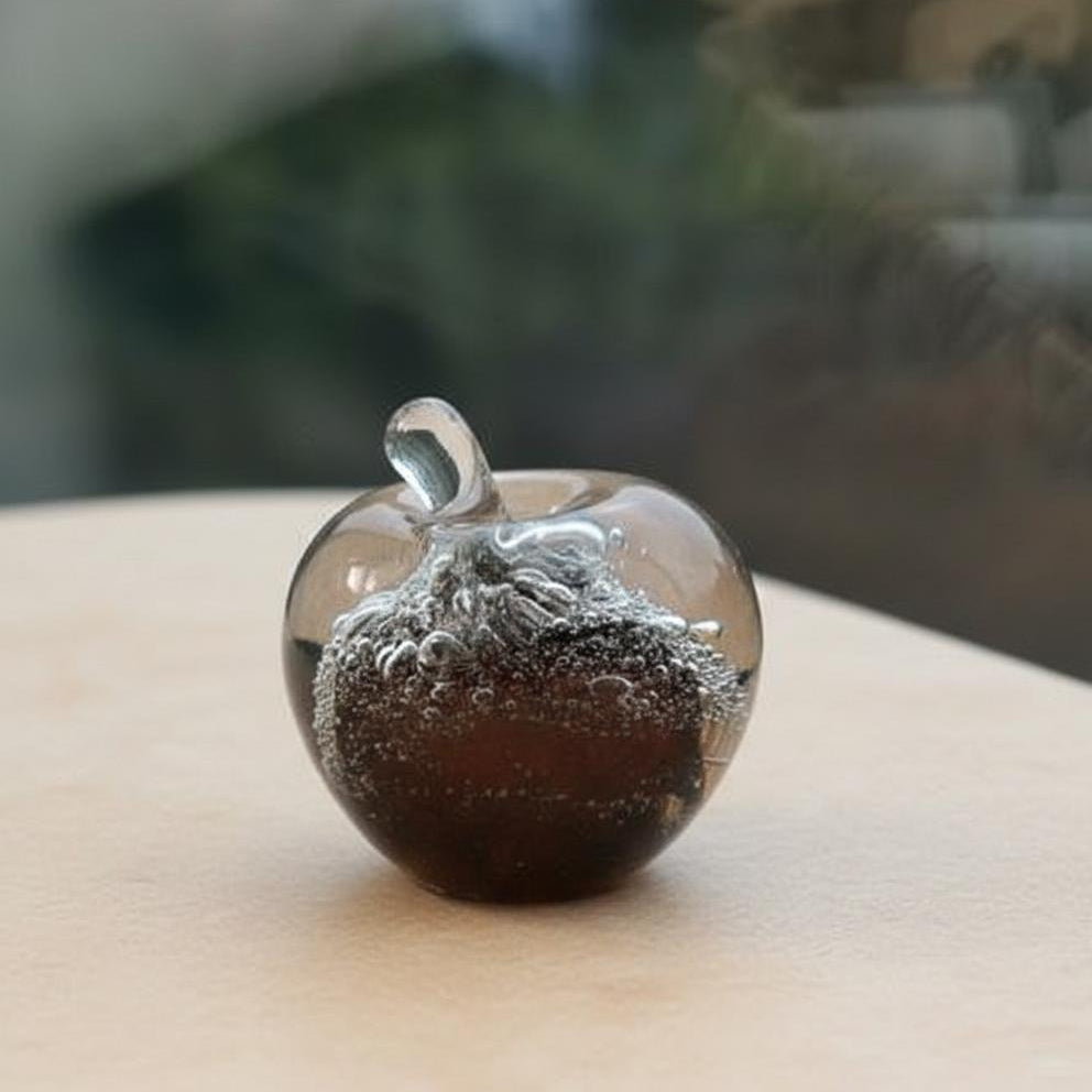 Small glass apple sculpture sitting on a wooden table