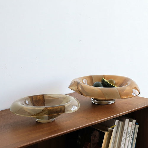 Two amber and milky art glass bowls on wooden shelf