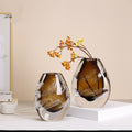 Two amber art glass vases with hand cut details on white table