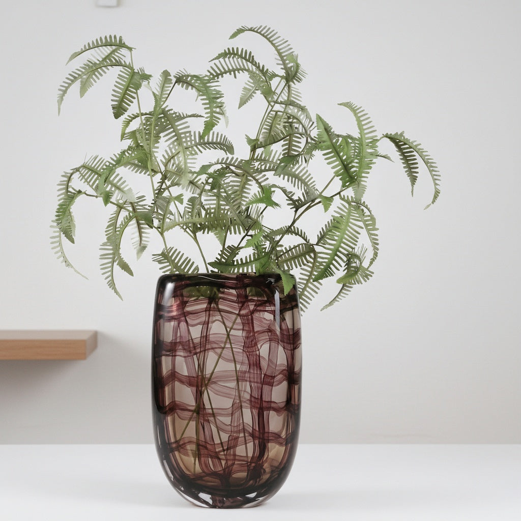 Large patterned glass vase styled with green ferns