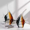 Two amber and black art glass angelfish sculptures on books
