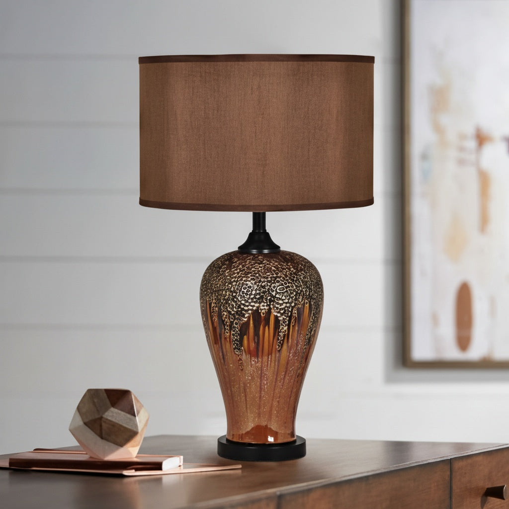 Front view of amber and bronze reactive glaze ceramic table lamp lit up