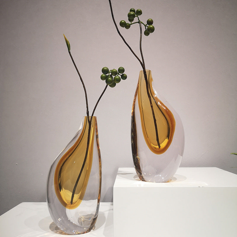 Amber and clear glass teardrop vases styled with green berries