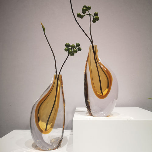 Amber and clear glass teardrop vases styled with green berries