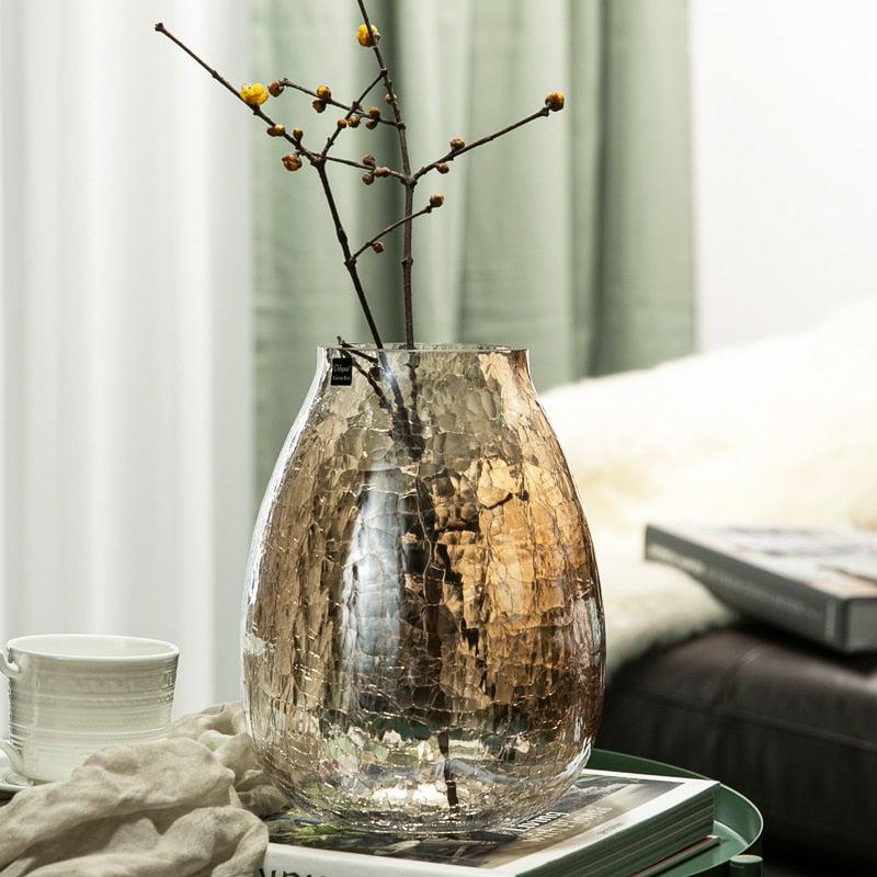 Amber crackle glass vase with branches on coffee table
