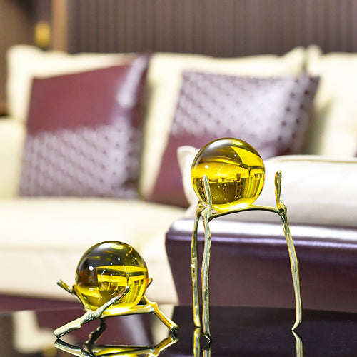Amber crystal sphere on gold branch stand in luxury living room setting