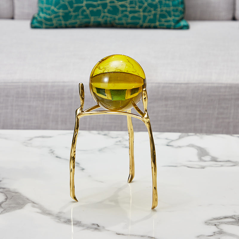 Close up of amber crystal orb on organic gold metal stand