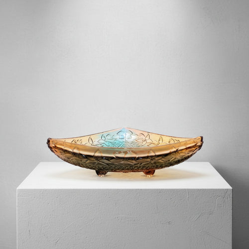 Side view of amber glass footed bowl showing floral embossing