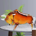 Side view of amber glass bull sculpture on marble table