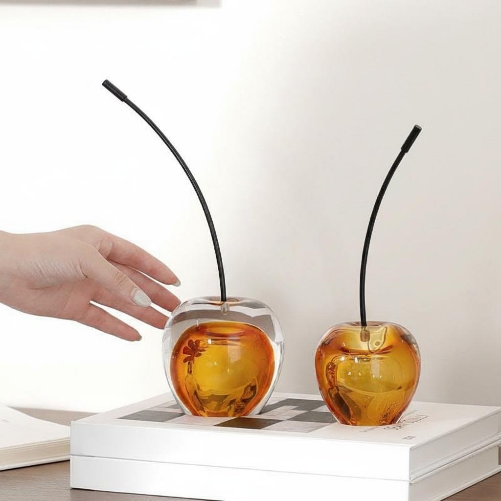 Amber glass cherry sculpture with black stem on books
