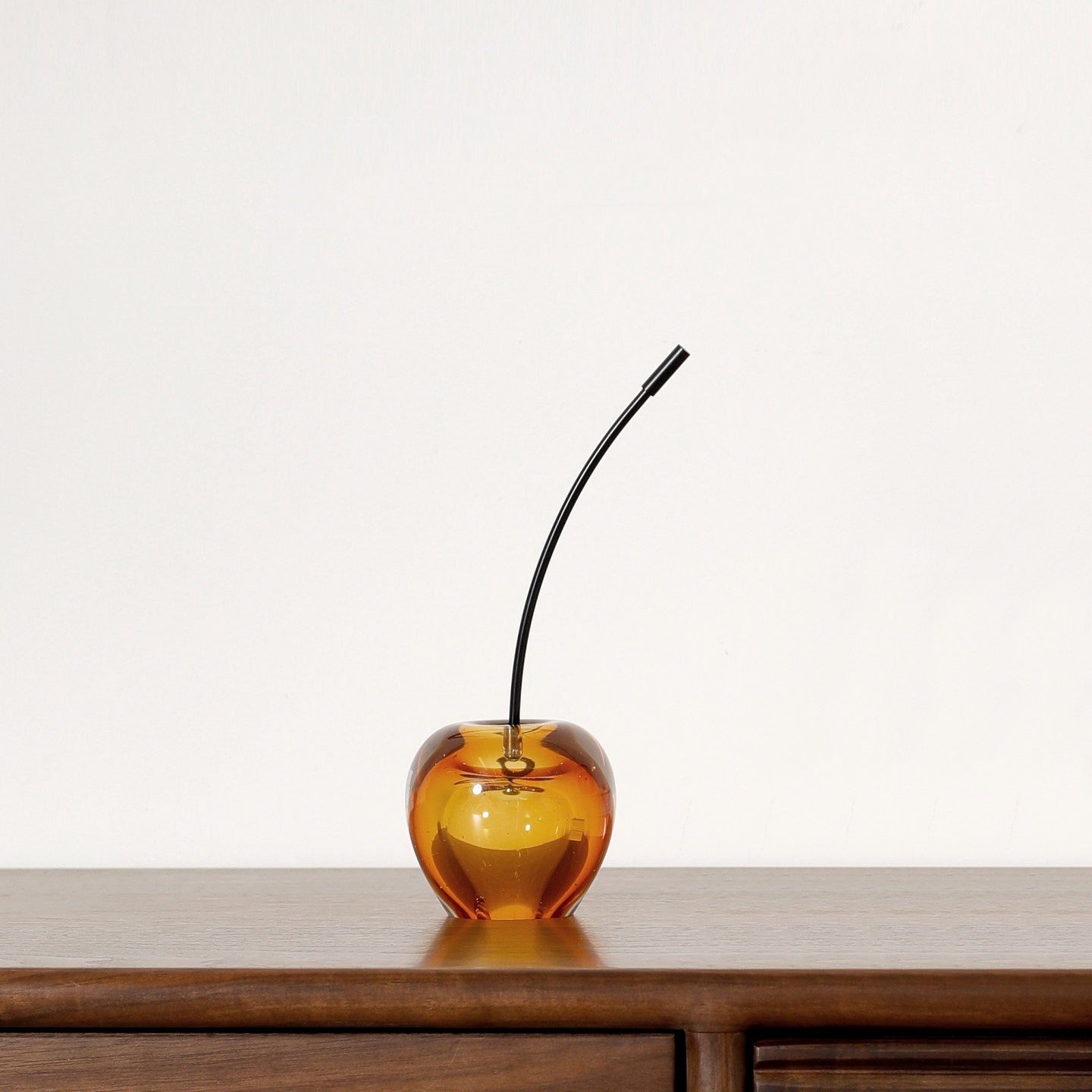 Amber glass cherry sculpture on wooden console