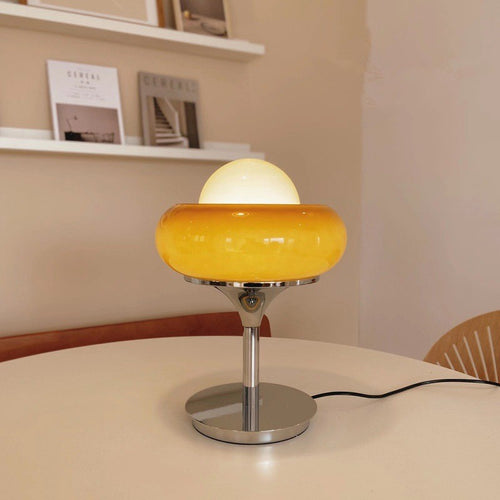 Illuminated amber glass table lamp showing warm glow on table