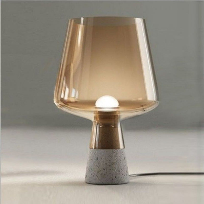 Front view of amber glass and concrete table lamp illuminated