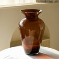 Empty amber glass flared vase on a white table