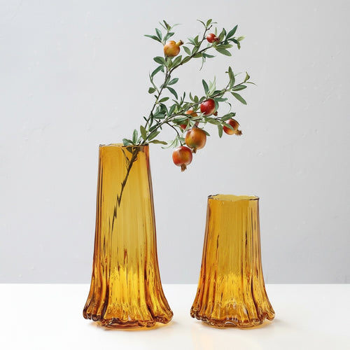 Two amber glass vases with organic wavy bases and pomegranate branches
