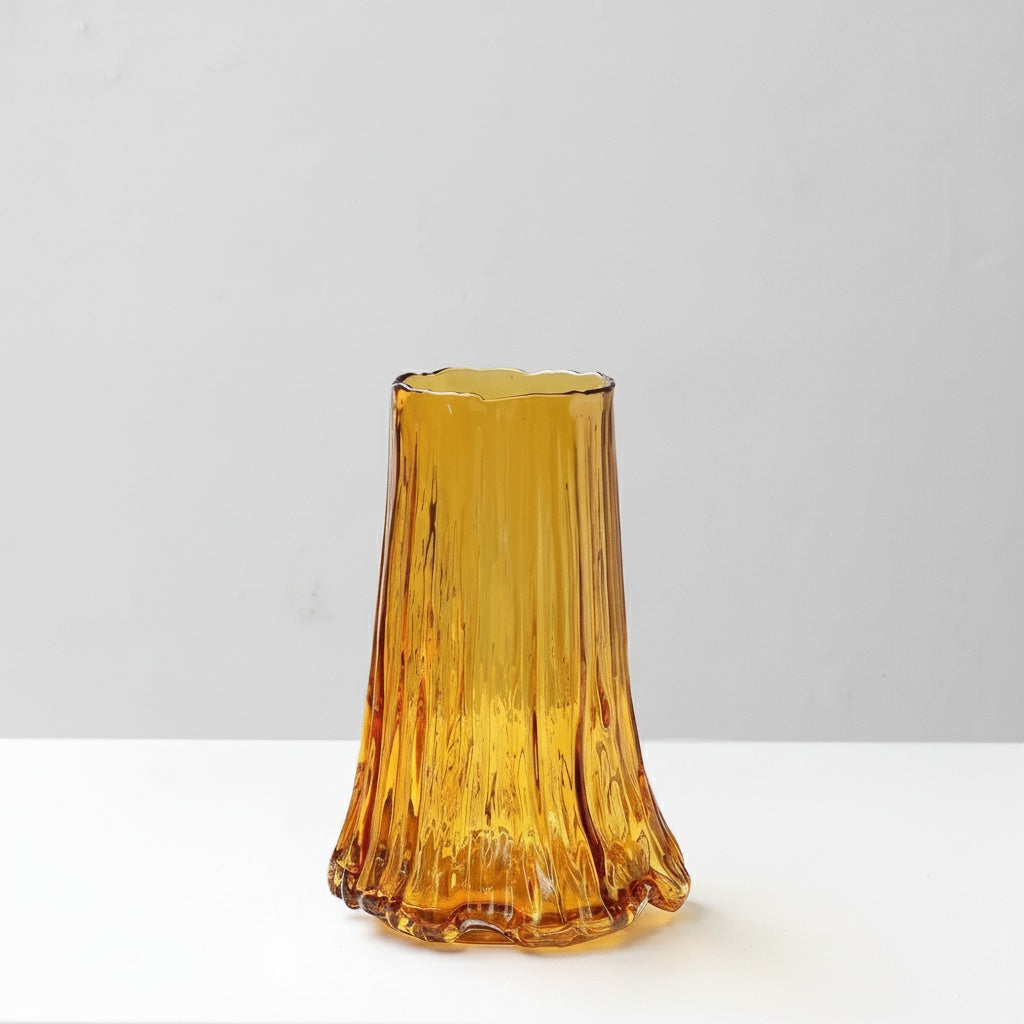 Medium amber glass vase with ribbed texture standing on white surface