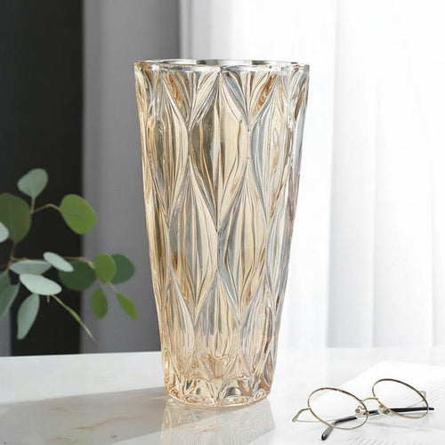 Amber glass geometric faceted vase on marble table with glasses