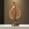 Front view of amber glass leaf sculpture on white surface