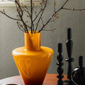 Amber glass vase with branches on table