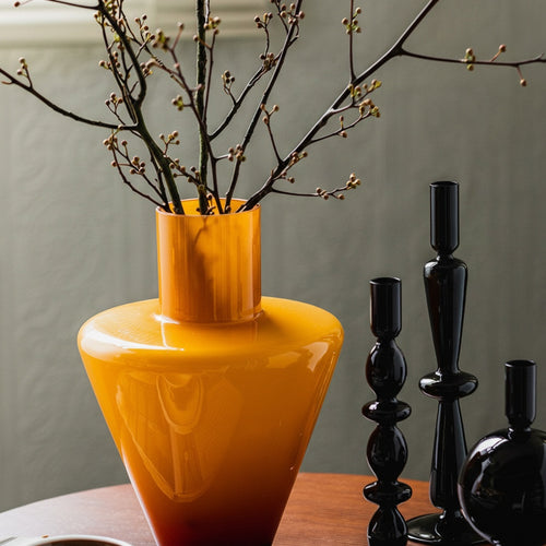 Amber glass vase with branches on table