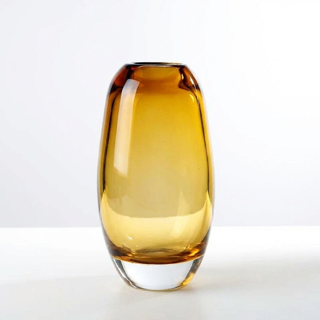 Amber gradient glass vase with solid clear base on books