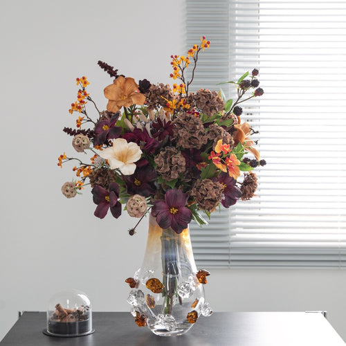 Amber gradient glass vase with floral arrangement on black table