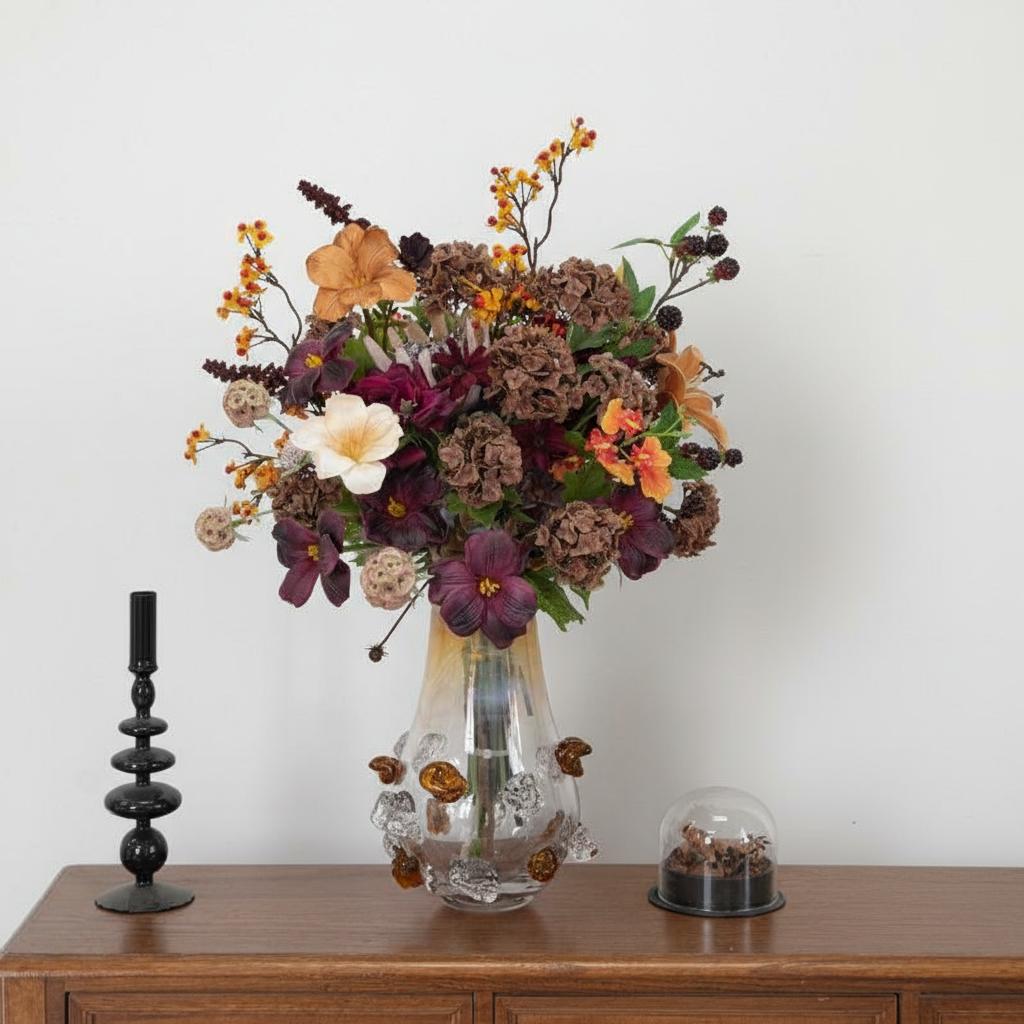 Front view of textured amber glass vase with dark floral bouquet