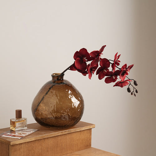 Textured amber glass vase with red orchids