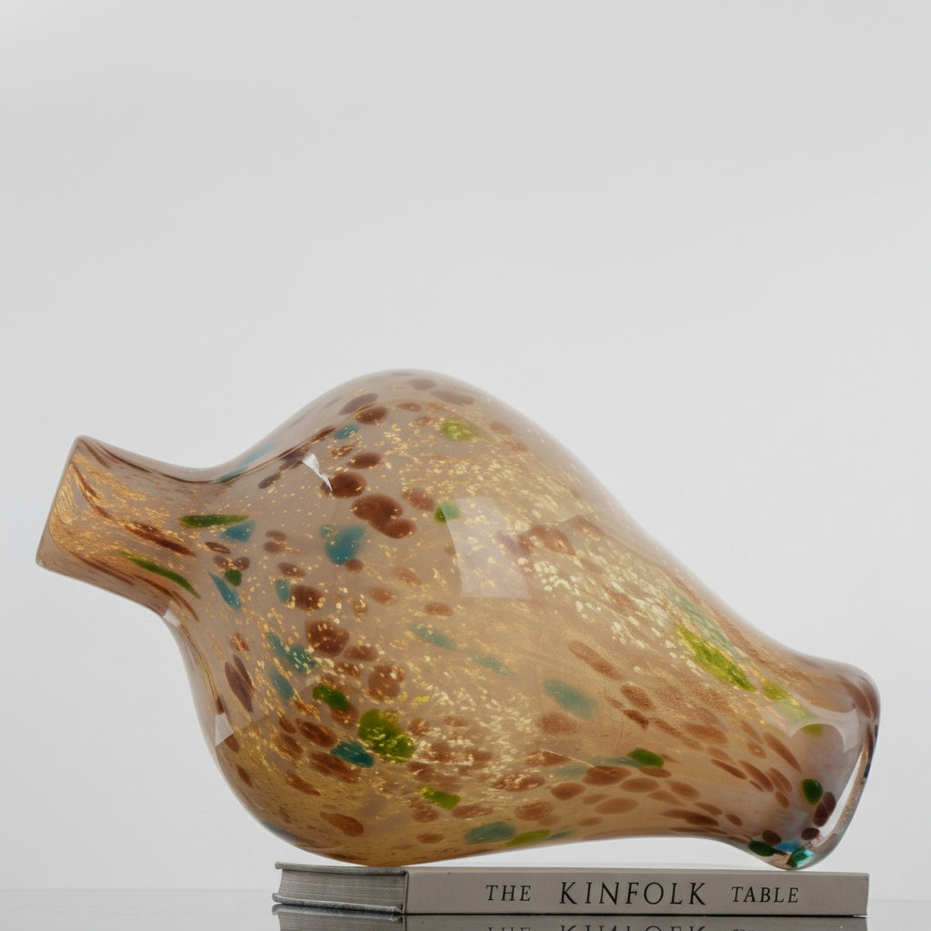 Side view of heavy amber glass vase resting on books