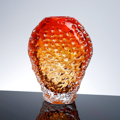 Front view of amber textured glass vase on reflective surface