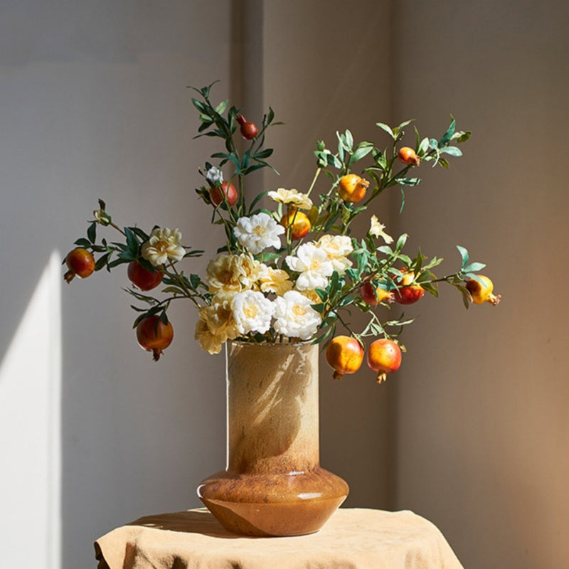 Amber textured glass vase with pomegranate flowers on table