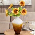 Two tone glazed glass vase holding sunflowers on wooden table