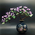 Close up of amethyst crystal and copper wire bonsai tree in blue ceramic vase