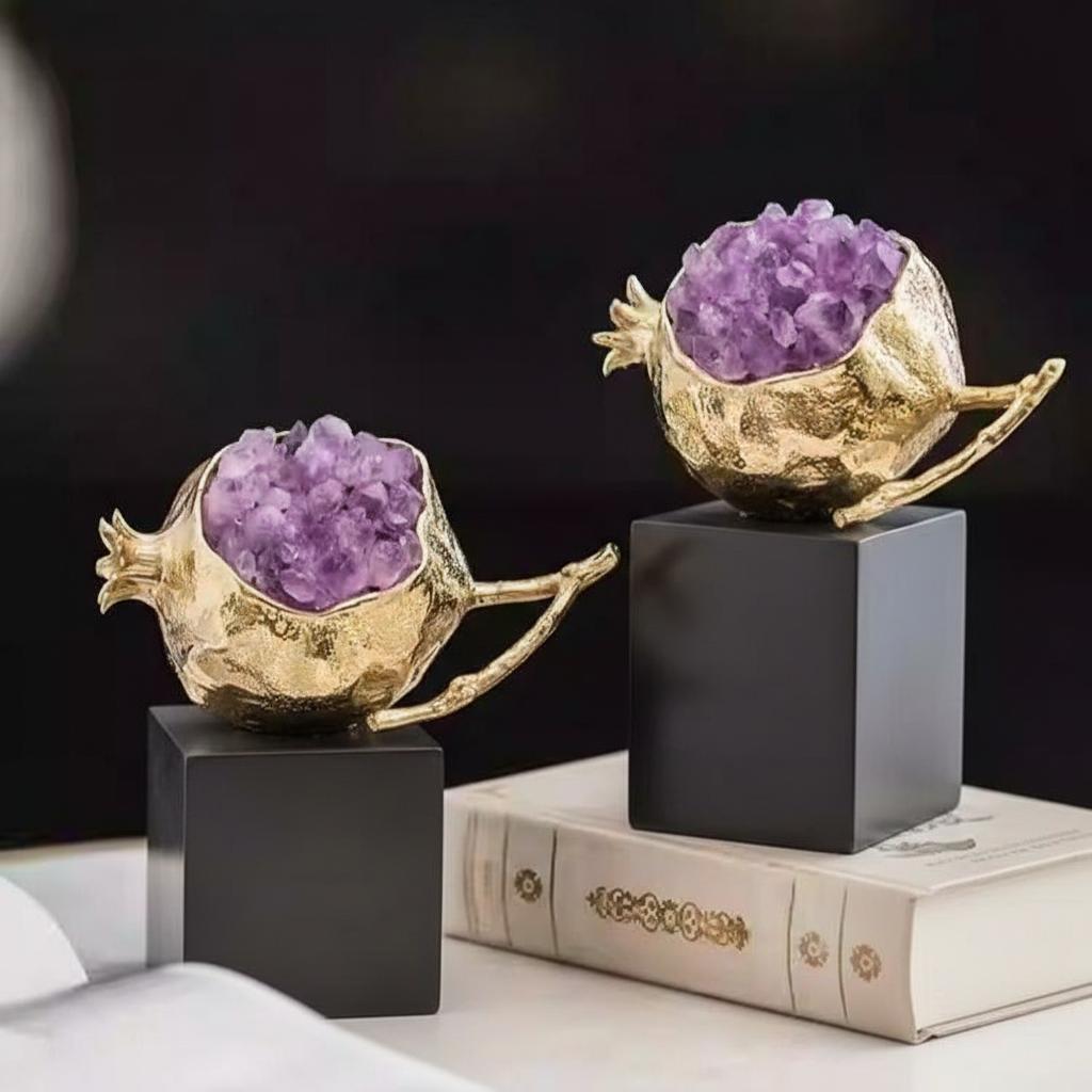 Two gold pomegranate sculptures displayed on books and table